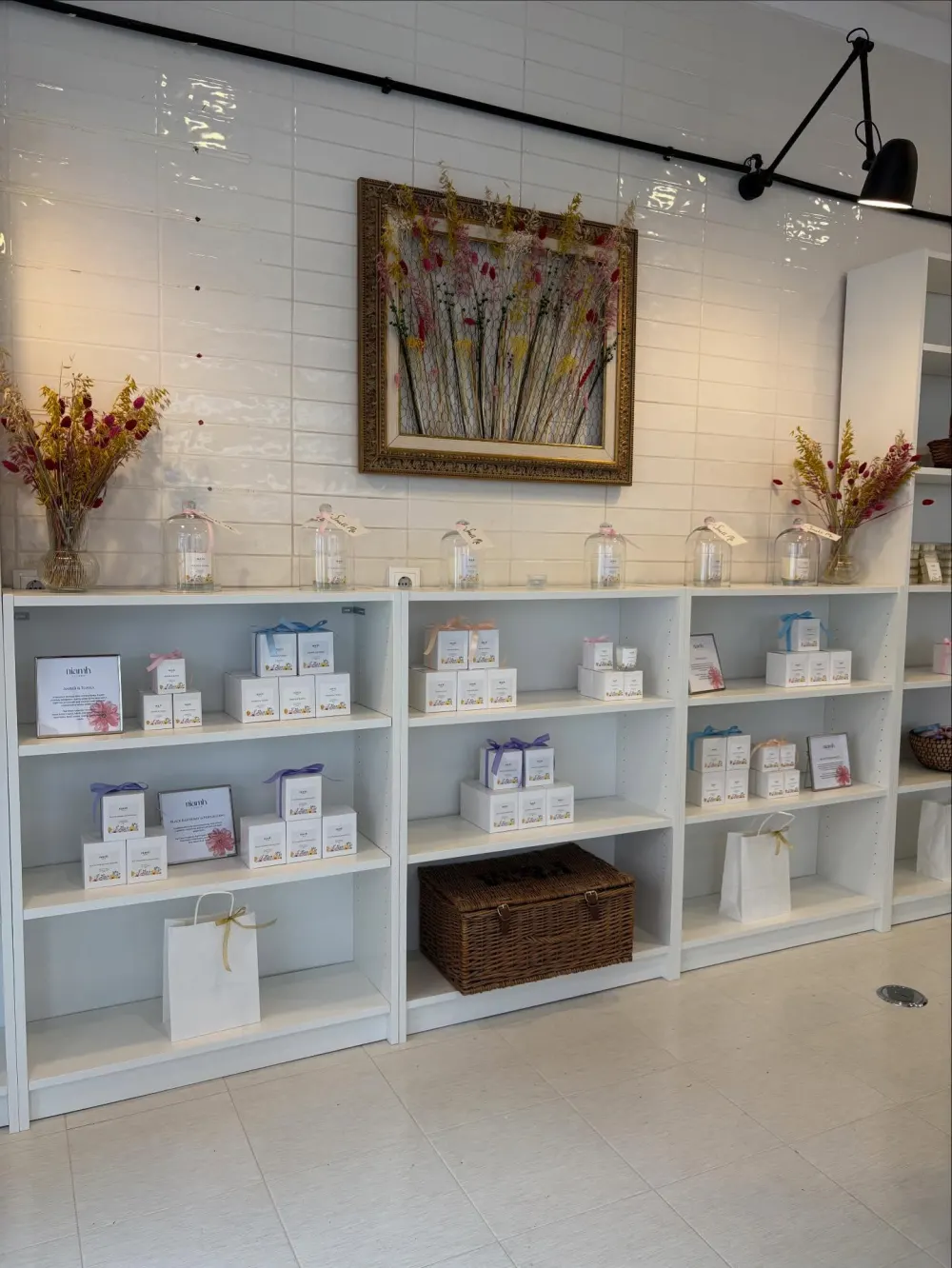 White shelves of boxed candles and dried flowers in Niamh's studio